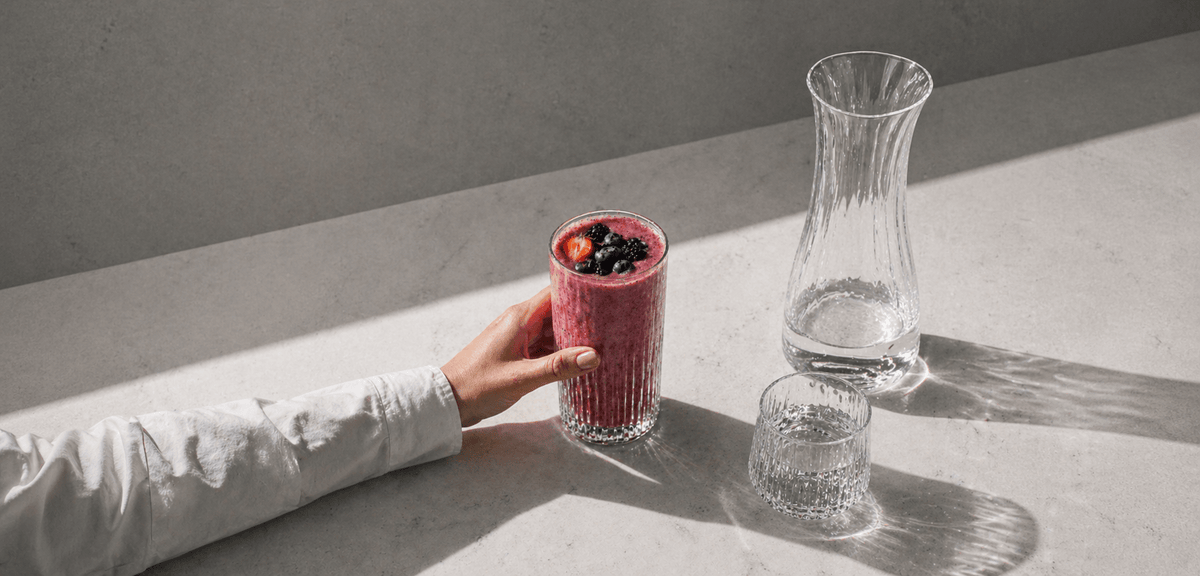 Kvinnehånd som tar et glass smoothie fra bordet
